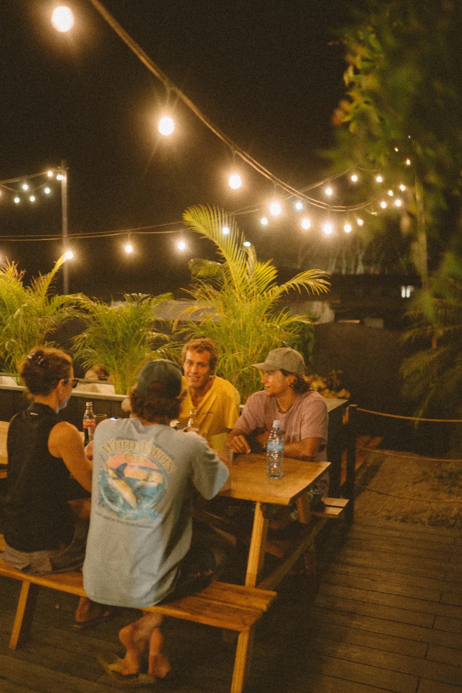 Guests sharing a table beneath the garden lights at ONDA Playa Grande