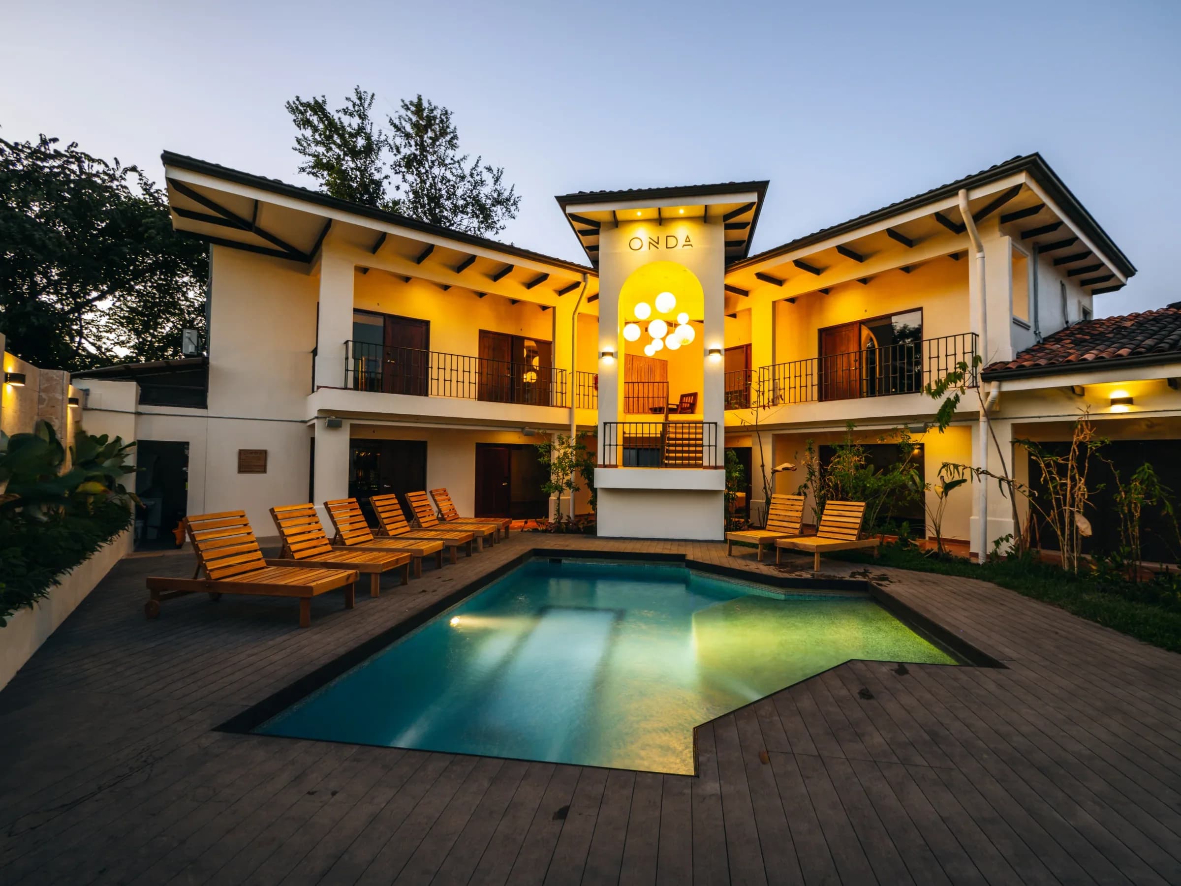 The illuminated ONDA Playa Grande building and courtyard pool at dusk